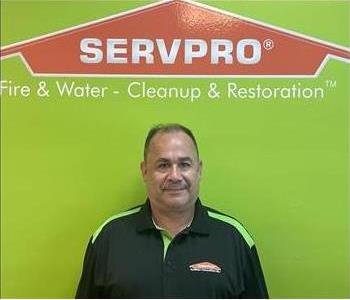 Man standing in front of green wall with SERVPRO logo
